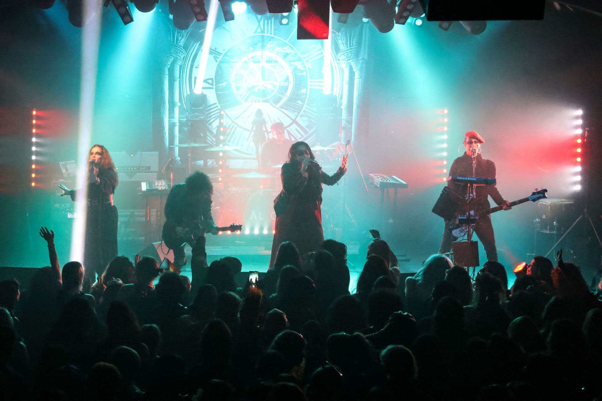 Wide shot of AL1CE on stage with light beams sweeping over a full audience